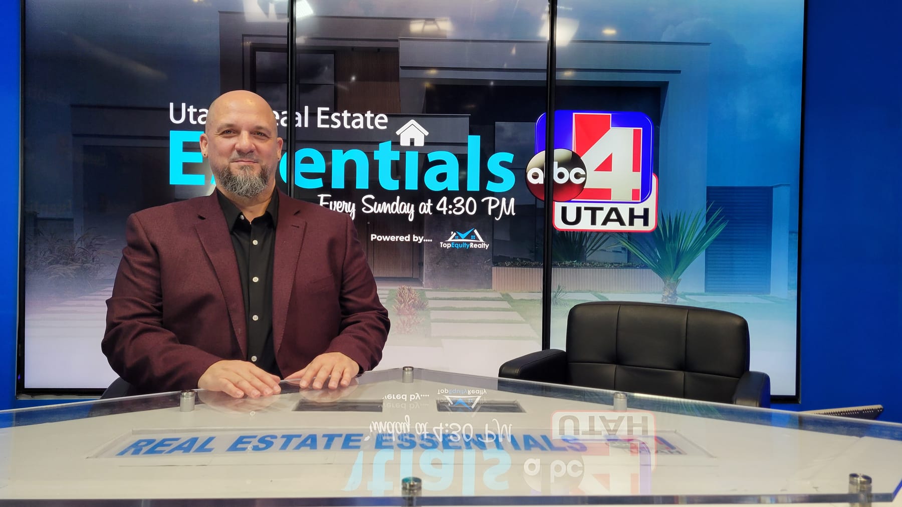 Micah Roquiero inside the Real Estate Essentials television studio with the production set and screens visible